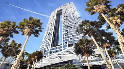 a tall building with palm trees in front of it at Address JBR: Beachfront Bliss & Sky-high Luxury in Dubai