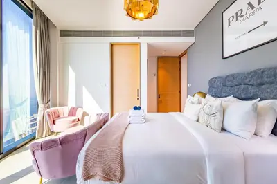 a bedroom with a large white bed with two pink chairs at Address JBR: Beachfront Bliss & Sky-high Luxury in Dubai