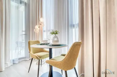 a dining room with a table and chairs next to a window at Enchanting Studio at Mesk 1 Midtown Dubai Production City by Deluxe Holiday Homes in Dubai