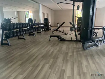 a gym with rows of exercise equipment on a wooden floor at Upscale Studio at Mesk 1 Midtown Dubai Production City by Deluxe Holiday Homes in Dubai
