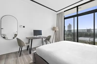 a bedroom with a bed and a desk with a mirror at ALiving Luxury Studio I Nicholas Residence, JVC in Dubai