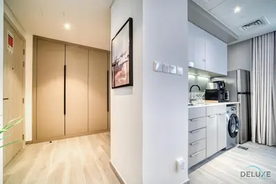 a kitchen with white cabinets and a washer and dryer at Tasteful Studio at Mesk 1 Midtown Dubai Production City by Deluxe Holiday Homes in Dubai