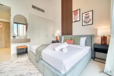 a bedroom with a large white bed in a room at Sleek Studio at UNA Town Square Dubailand by Deluxe Holiday Homes in Dubai