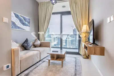 a living room with a couch and a large window at Staycae Holiday Homes - ZADA in Dubai