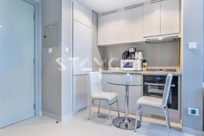 a kitchen with a glass table and white chairs at Staycae Holiday Homes - ZADA in Dubai