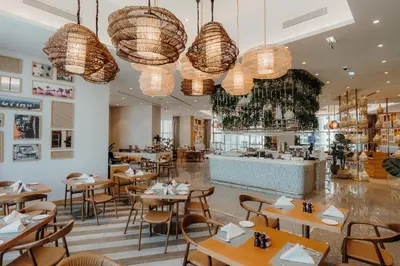 a restaurant with tables and chairs and chandeliers at Staycae Holiday Homes - ZADA in Dubai