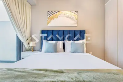 a bedroom with a large white bed with a blue headboard at Staycae Holiday Homes - ZADA in Dubai