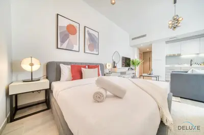 a bedroom with a large white bed with red pillows at Polished Studio at Mesk 1 Midtown Dubai Production City by Deluxe Holiday Homes in Dubai