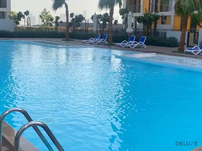 a swimming pool with blue chairs in a building at Polished Studio at Mesk 1 Midtown Dubai Production City by Deluxe Holiday Homes in Dubai