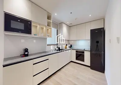 a kitchen with white cabinets and a black refrigerator at Upgraded 1Bedroom next to JBR Tourist Destination in Dubai