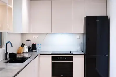 a kitchen with white cabinets and a black refrigerator at Upgraded 1Bedroom next to JBR Tourist Destination in Dubai