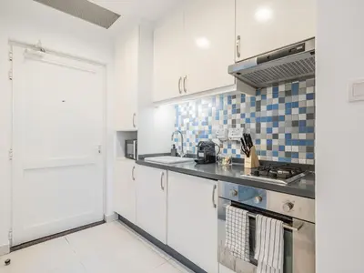a kitchen with white cabinets and blue tiles on the wall at Paradise Studio in Palm Views - Palm Jumeirah in Dubai