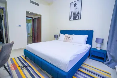 a bedroom with a large bed with a blue frame at Alashrafia Saray- Superior 1BR apartment in Sport City in Dubai
