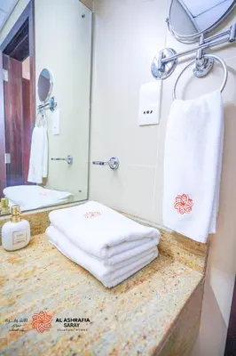 a bathroom with towels on a counter with a mirror at Alashrafia Saray- Superior 1BR apartment in Sport City in Dubai