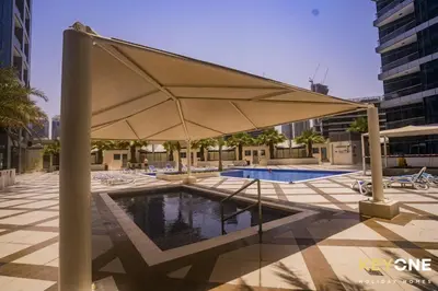 a pool with a large umbrella in a courtyard at Chic Marina View Living in a Two Bedroom in Dubai