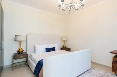 a white bedroom with a white bed and a chandelier at CitiHome- Modern- 1BR Creek Residence in Dubai