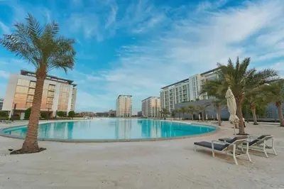 a large swimming pool with palm trees and buildings at Panoramic 1br with Crystal Lagoon & Downtown View in Dubai