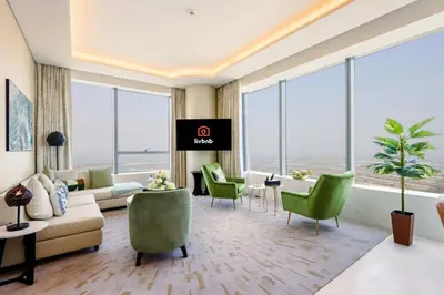 a living room with a couch and chairs and windows at Livbnb - 1BR w/Spectacular Sea Views in Palm Tower in Dubai