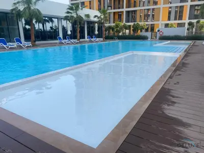 a large swimming pool with blue chairs and a building at Distinguished Studio at Mesk 1 Midtown Dubai Production City by Deluxe Holiday Homes in Dubai