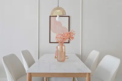 a dining room table with white chairs and a vase with flowers at Silkhaus luxurious 1BDR in AG Tower, Business Bay in Dubai