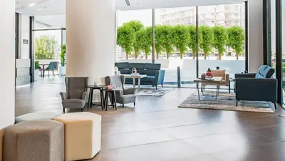 a lobby with chairs and tables and windows at Pyramisa Hotel Apartments in Dubai