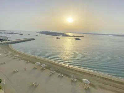 a beach with chairs and umbrellas and the ocean at Trophy 2BDR Sandy Shores Retreat with Panoramic Sea View & Private Beach Access in Dubai