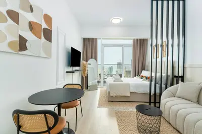 a living room with a couch and a bed and a table at Cozy studio at Bloom Height - JVC in Dubai