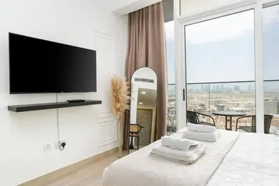 a white bedroom with a flat screen tv and a bed at Cozy studio at Bloom Height - JVC in Dubai