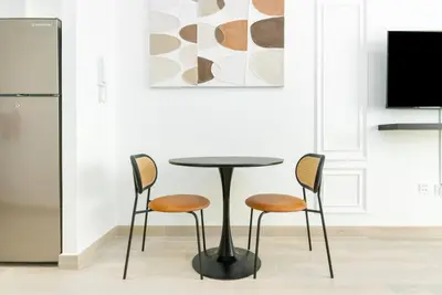 a table and chairs in a kitchen with a painting at Cozy studio at Bloom Height - JVC in Dubai