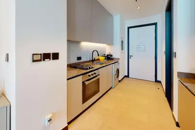 a kitchen with white cabinets and a wooden floor at 15 Northside - Chic Studio in Dubai