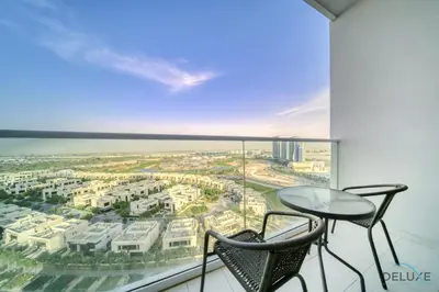 a balcony with a table and chairs and a large window at Delightful Studio at Carson A DAMAC Hills Dubailand by Deluxe Holiday Homes in Dubai