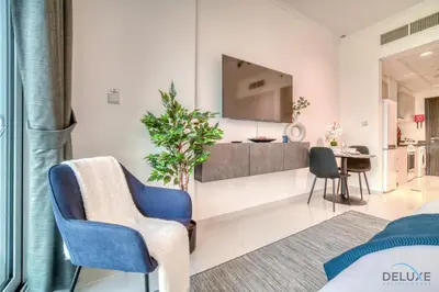 a living room with two chairs and a tv at Delightful Studio at Carson A DAMAC Hills Dubailand by Deluxe Holiday Homes in Dubai