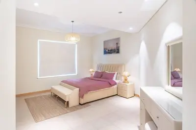 a white bedroom with a bed and a window at Dubai The Palm 4BR Beach & Pool Access in Dubai