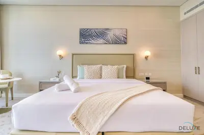 a large white bed in a room with a table at Heavenly Studio at The Palm Tower Palm Jumeirah by Deluxe Holiday Homes in Dubai