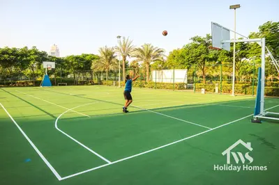 a woman hitting a tennis ball on a tennis court at The Urban Oasis - Serenity in Dubai