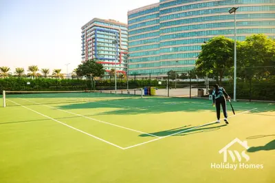 a woman playing tennis on a tennis court at The Urban Oasis - Serenity in Dubai