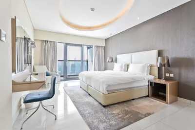 a bedroom with a bed and a desk and a chair at ALiving Elite 2BR I Burj Khalifa View I Paramount Towers, 6102 in Dubai