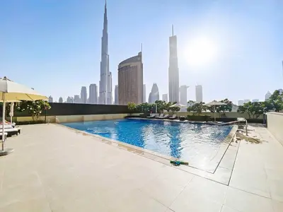 a swimming pool with a city skyline in the background at Silkhaus modern 1BDR in Downtown with balcony, pool, gym in Dubai