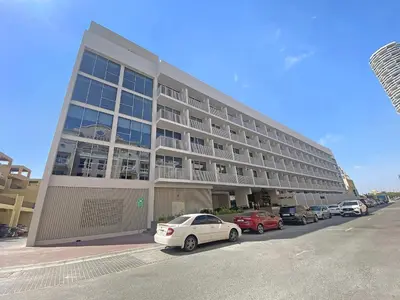a large building with cars parked in a parking lot at Silkhaus new furnished studio in JVC, Luma 21 in Dubai