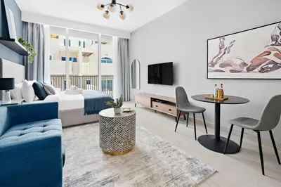 a hotel room with a blue couch and a bed and a table at Silkhaus new furnished studio in JVC, Luma 21 in Dubai