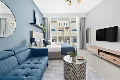 a living room with a blue couch and a bed at Silkhaus new furnished studio in JVC, Luma 21 in Dubai