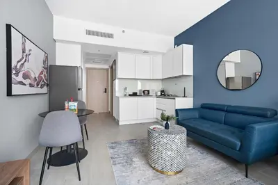 a living room with a blue couch and a table at Silkhaus new furnished studio in JVC, Luma 21 in Dubai