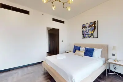 a bedroom with a large white bed with blue pillows at O Ten, Al Jaddaf - Smart One Bedroom in Dubai