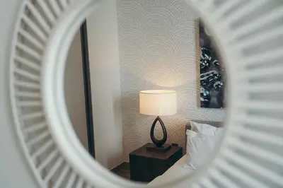 a mirror reflecting a bedroom with a lamp on a table at Maison de Luxe - Jumeirah Living Marina Gate in Dubai