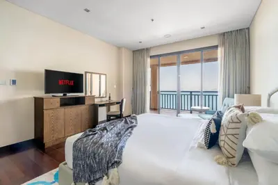 a bedroom with a large white bed and a television at GuestReady - Posh Living with Burj Al Arab view in Dubai