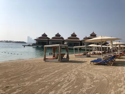 a beach with chairs and umbrellas and the water at GuestReady - Posh Living with Burj Al Arab view in Dubai