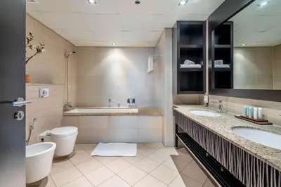 a bathroom with two sinks and a toilet and a tub at GuestReady - Burj Al Arab view at Royal Amwaj in Dubai