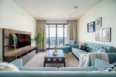 a living room with blue couches and a tv at GuestReady - Burj Al Arab view at Royal Amwaj in Dubai