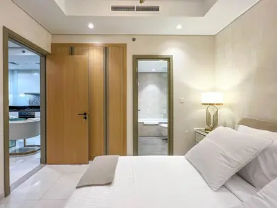 a bedroom with a white bed and a bathroom at Keyrock Living - Burj Khalifa View Retreat with Pool in Dubai