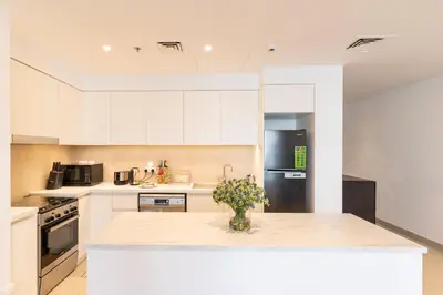 a kitchen with white cabinets and a black refrigerator at Spacious 2 Bedroom on High Floor in Creek Horizon - Allsopp&Allsopp in Dubai
